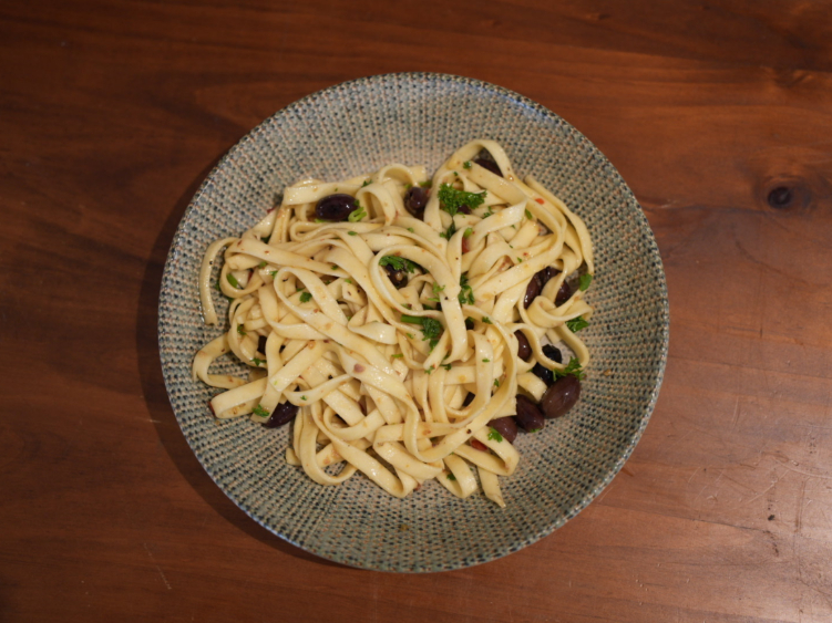 Fettuccine with mushrooms and greens on a speckled plate