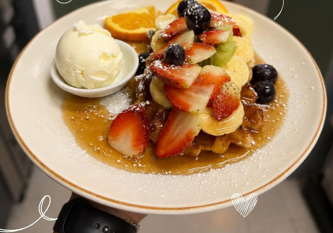 Breakfast waffles with strawberries, blueberries, orange, ice cream and maple syrup