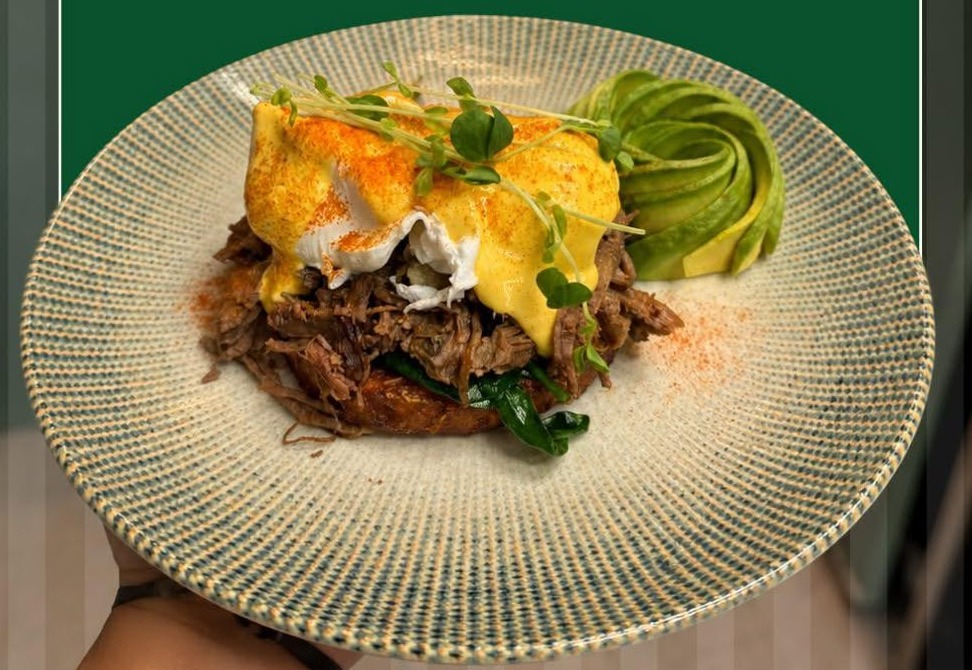 Rasa Classic Pulled Lamb Benedict with hollandaise and an avocado rose on a speckled plate